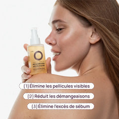 A woman in profile holds a bottle of VOEY pre-shampoo. The bottle is a warm golden yellow with a white pump dispenser.